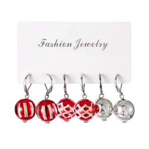Gros plan de trois paires de boucles d'oreilles boules de Noël avec imprimés festifs