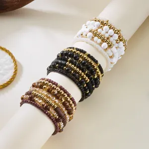 Close-up detail of stacked Bohemian beaded bracelets in white, black, and brown