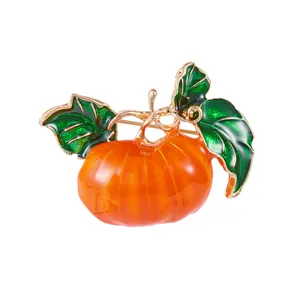 Detailansicht einer orangefarbenen Kürbis-Brosche mit grünen Blättern und Goldrand