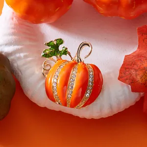 Detailansicht einer orangefarbenen Kürbisbrosche aus Emaille mit funkelnden Kristallen