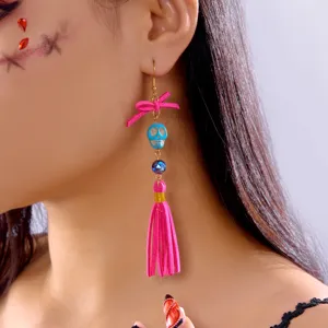Detailed close-up of vibrant pink tassel earrings featuring a blue skull bead and bow