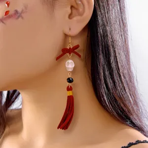 Detailed view of Halloween themed earring featuring a red bow, white skull, and tassel