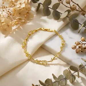 Detailed macro view of a gold tulip petal bracelet with sparkling inlaid zircons on marble backdrop.