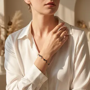 Elegant gold-tone bracelet with blue gemstone leaf accents worn on a woman's wrist