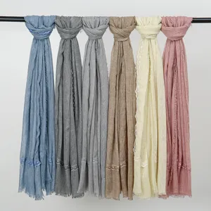 Close up view of multi-color crinkled texture scarves with delicate lace trim hanging neatly.
