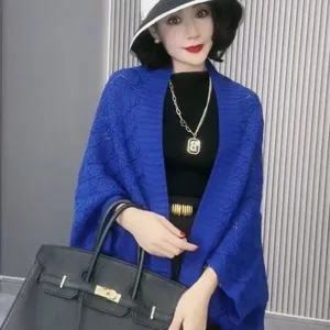 Details van de blauwe gebreide damessjaal cape met opengewerkte textuur voor de lentemode.