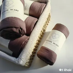 Gros plan détaillé d'un foulard en coton uni enroulé en kaki, joliment présenté en panier.