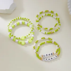 Close-up of lime green and white beaded tennis bracelet set with LOVE and TENNIS beads