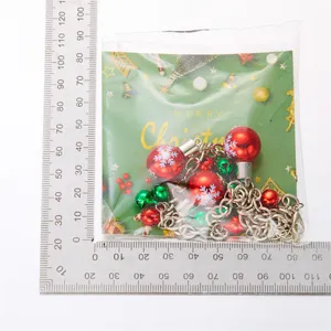 Festliche Weihnachtskette mit bunten Glocken und Schneeflockenbällen in Verpackung mit Lineal.