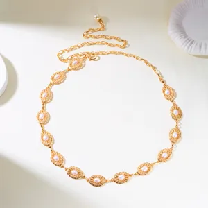 Close-up of vintage gold waist chain with carved oval links and pink pearl beads