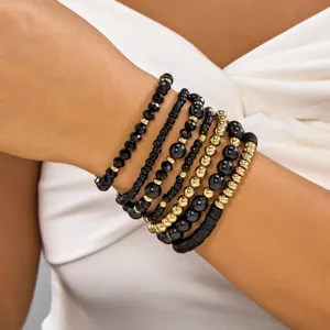 Detailed view of Bohemian black faceted crystal and gold beaded stacked bracelets on wrist