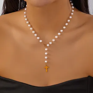 Close-up detail of elegant rosary-style pearl necklace with a gold cross pendant