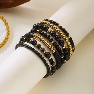 Detail view of black and gold beaded bracelet set with various bead textures and shapes.