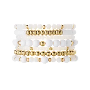 Detailed macro view of bohemian stacked bracelet set featuring white and gold metallic beads