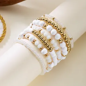 Close-up of Bohemian stacked beaded bracelets with gold and white accents