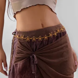 Detail of vintage gold flower waist chain on brown fabric.