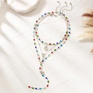 Detailed close-up of a layered necklace set with vibrant colorful rhinestones and cross
