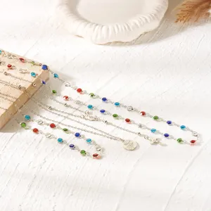 Detailed view of layered silver chains with colorful rhinestones and cross pendant