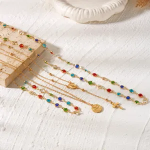 Close-up of gold-plated layering necklaces with colorful rhinestones and cross pendant