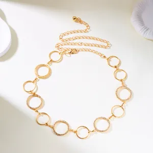 Detail view of gold metal body chain with hollow rhinestone-encrusted circular links.