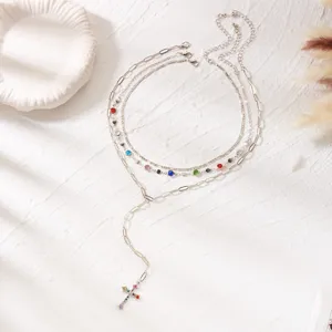 Detail view of layered silver-tone necklaces with colorful rhinestones and cross pendant