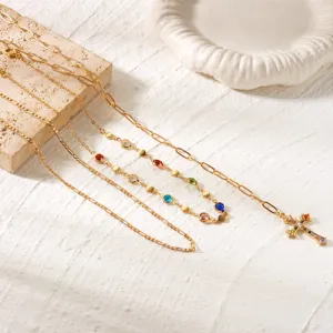 Layered gold-tone necklace set with colorful rhinestone cross pendant and multi-gem accents