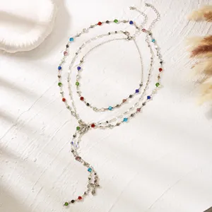 Detailed view of layered silver necklace set with vibrant colorful rhinestones and cross