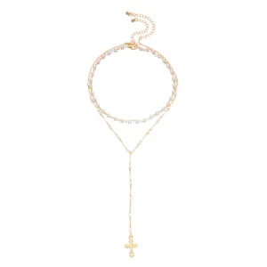Detailed view of an elegant gold layered necklace featuring small pearls and a cross pendant