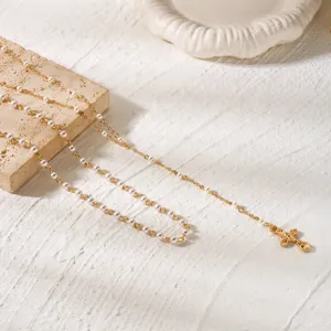Elegant gold cross pendant necklace featuring a delicate pearl beaded chain for women.