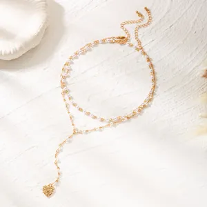 Double-layered gold necklace with white pearls and a heart pendant on white background