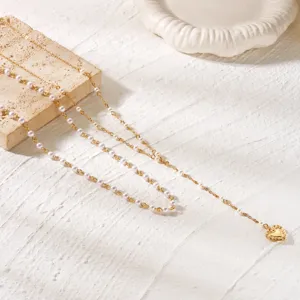 Detailed view of a gold chain necklace with delicate white pearls and a heart-shaped pendant.