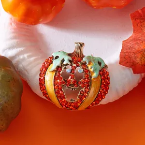 Detailansicht einer Halloween-Kürbisbrosche mit roten Strasssteinen und Emaille-Finish.