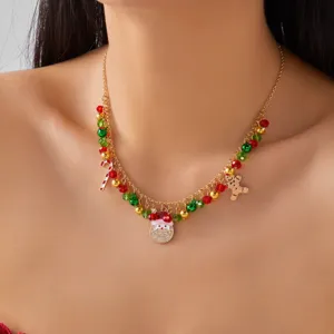 Detalle de un collar navideño dorado con dijes de Papá Noel y el hombre de jengibre