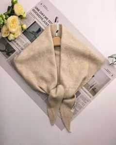 Detail van beige gebreide driehoekige sjaal, zachte wolblend stof, elegant dagelijks accessoire.