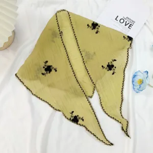 Gros plan sur le foulard triangulaire en coton et lin vert avec de superbes motifs floraux noirs.