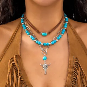 Detail view of model wearing a three-layer western necklace with bull skull and turquoise