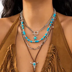 Close-up of layered western cowboy necklace set with turquoise and bull head pendant.