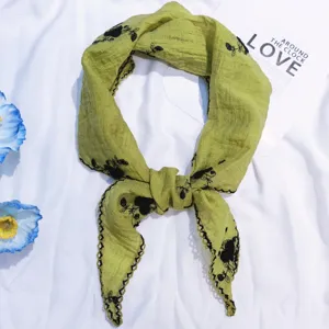 Vue détaillée du foulard triangulaire brodé de fleurs en coton et lin vert, coiffure polyvalente.