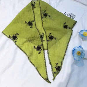 Vue détaillée du foulard triangulaire en lin et coton vert avec broderie florale noire.
