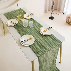 Bohemian green cheesecloth table runner detail showcasing soft pleated gauze texture.