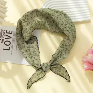 Detail view of green floral cotton linen triangle scarf with black scalloped edge.