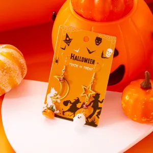 Detalle de pendientes de Halloween con amuletos de fantasma y calabaza en luna y estrella