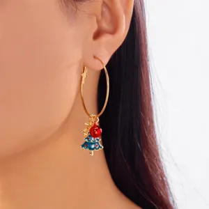 Close-up of a festive gold hoop earring featuring a blue Christmas tree and red ball charm