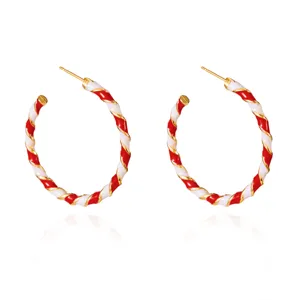 Festive red and white candy cane style twisted enamel hoop earrings with gold accents