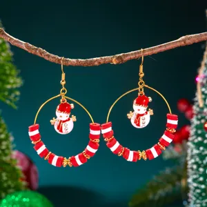 Nahaufnahme von weihnachtlichen Schneemann-Ohrringen mit roten und weißen Perlen.