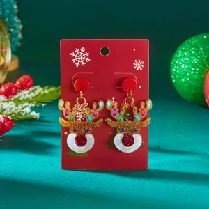 Detailed view of glittering Christmas reindeer acrylic earrings on a red display card