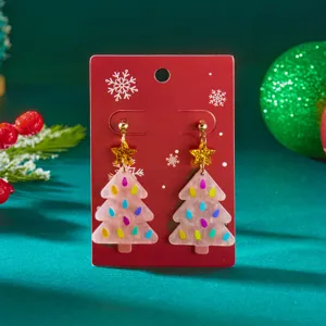 Close-up of festive pink acrylic Christmas tree earrings with star studs on red card