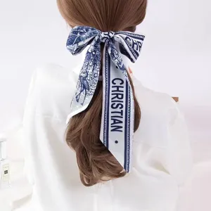 Detail view of a blue and white printed silk hair ribbon scarf tied elegantly in a ponytail.