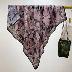 Gedetailleerd overzicht van de luxueuze tweekleurige zijden wollen sjaal met botanische print.