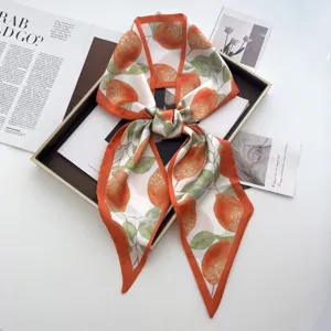 Detailed view of stylish orange citrus print silk ribbon scarf with vibrant color border.
